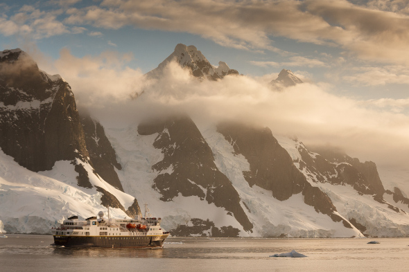  ship cruising infront of snow-capped cliffs